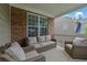 Inviting covered brick patio featuring comfortable wicker seating for relaxing outdoors at 202 Roseman Way, Woodstock, GA 30188
