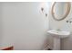 Clean powder room features a pedestal sink and a round mirror at 2335 Corbett Ct, Powder Springs, GA 30127