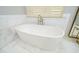 Bright bathroom featuring a modern soaking tub with marble flooring and tiled accent wall at 4645 Wykeshire Ct, Cumming, GA 30041