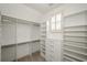 Spacious walk-in closet featuring custom shelving, drawers, and a window for natural light at 4645 Wykeshire Ct, Cumming, GA 30041