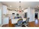 Bright kitchen with white cabinets, stainless appliances, an island with bar seating, and an elegant dining table at 4645 Wykeshire Ct, Cumming, GA 30041