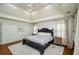 Bright bedroom showcasing large bed, tray ceilings, wood floors, neutral rug, and natural light from shuttered windows at 4645 Wykeshire Ct, Cumming, GA 30041