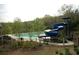 Community pool features a slide, gated fence, lounge chairs, and mature tree border for privacy at 4645 Wykeshire Ct, Cumming, GA 30041
