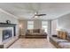 Cozy living room featuring a fireplace, plush sofas, ceiling fan and hardwood flooring at 932 Sugar Meadow Ln, Sugar Hill, GA 30518