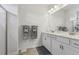 The bright bathroom features double sinks, white vanity cabinets, and a glass enclosed shower at 1181 Chastain Dr, Sugar Hill, GA 30518