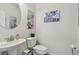 Well-lit half bathroom features a pedestal sink, round mirror and modern decor at 1181 Chastain Dr, Sugar Hill, GA 30518