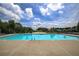Outdoor pool with sun loungers, umbrellas, and water features surrounded by trees at 4460 Greycliff Pte, Douglasville, GA 30135