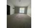 A carpeted living room features a large window providing natural light, freshly painted walls, and vaulted ceilings at 6361 Redan Sq, Lithonia, GA 30058