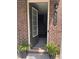 Inviting brick home entrance with a welcoming open door, black door hardware and ferns at 531 Headwind Way, Alpharetta, GA 30005