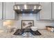 Stovetop featuring gray cabinets and granite countertops with stainless steel ventilation at 531 Headwind Way, Alpharetta, GA 30005