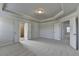 Spacious primary bedroom with tray ceiling, carpet, and access to ensuite bathrooms at 4250 Pembia Dr, Cumming, GA 30028