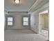A spacious bedroom with a tray ceiling and two windows allowing for natural light at 4250 Pembia Dr, Cumming, GA 30028