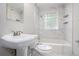 Bathroom featuring a tiled shower-bath, a glass block window and white fixtures at 2721 Glenvalley Dr, Decatur, GA 30032