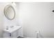 Clean and modern half-bathroom with pedestal sink, oval mirror, and dark wood-look flooring at 320 Crider Ct, Woodstock, GA 30188