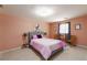 Comfortable bedroom featuring neutral carpet, pink walls, a gray headboard and natural light at 440 Barrington W Dr, Roswell, GA 30076