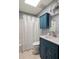 Well-lit bathroom featuring a skylight, blue vanity, and shower with tub at 1392 Cornwall Rd, Decatur, GA 30032