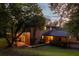 Backyard view of a brick house featuring a deck and outdoor lighting among mature trees at 1392 Cornwall Rd, Decatur, GA 30032