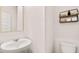 Bright powder room with a modern toilet, pedestal sink, and decorative wall shelf at 321 Sound Cir, Stockbridge, GA 30281