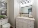 Stylish half-bath features a white vanity, decorative mirror, and elegant floral artwork at 361 Princeton Way, Lawrenceville, GA 30044