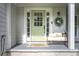 This home's entrance has a light green door, wreath, and a bench with cushions and pillows at 361 Princeton Way, Lawrenceville, GA 30044