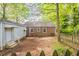 View of the brick home's backyard showing a wood fence, some mature trees, and grass at 879 Sylvan Sw Pl, Atlanta, GA 30310