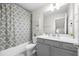 Well-lit bathroom featuring a shower-tub, gray vanity, framed mirror, framed art and a decorative shower curtain at 774 Belrose Dr, Smyrna, GA 30080