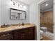 Bathroom featuring granite counters, dark wood vanity, framed mirror, and glass enclosed shower at 1572 Azalea Dr, Lawrenceville, GA 30043