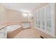 Main bathroom featuring tile floors, jacuzzi tub, and large window with plantation shutters at 2140 Old Orchard Lane Ln, Canton, GA 30114