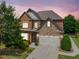 Inviting brick home with stone accents, manicured lawn, and an attached two-car garage at sunset at 3015 Arbor Song Ct, Cumming, GA 30041