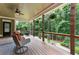 Relaxing covered back porch featuring outdoor seating, ceiling fan, and scenic views of the lush backyard landscape at 32 Pullman Trl, Acworth, GA 30101