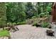 Beautiful backyard with a stone patio, wooden chairs, and a waterfall feature surrounded by lush greenery at 32 Pullman Trl, Acworth, GA 30101