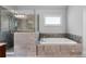 Bathroom featuring stone-look tile walls surrounding the bathtub and clear glass shower at 32 Pullman Trl, Acworth, GA 30101