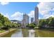 Scenic view of a pond with a fountain, surrounded by lush greenery and modern city buildings in the background at 390 17Th Nw St # 2005, Atlanta, GA 30363