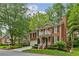 View of charming brick home with a two car garage, mature trees and lush landscaping on a sunny day at 1117 Haven Glen Ne Ln, Brookhaven, GA 30319