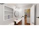 Neutral bathroom with white shelves, dark wood cabinets, a circular mirror and modern light fixtures at 310 Willow Ln, Temple, GA 30179