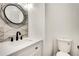 Modern half-bath with unique circular mirror and vessel sink atop white vanity at 1226 Kelly Nelson Ct, Lawrenceville, GA 30043