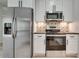 A clean, white kitchen is accented by stainless steel appliances and a decorative tiled backsplash at 1226 Kelly Nelson Ct, Lawrenceville, GA 30043