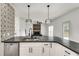 Modern kitchen with gray countertops, sleek stainless appliances, and decorative backsplash leading into living area at 1226 Kelly Nelson Ct, Lawrenceville, GA 30043