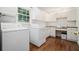 Well-lit laundry room with white appliances, cabinetry and hardwood floors; perfect for easy chores at 1691 Houghton N Ct, Atlanta, GA 30338