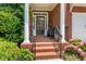 Inviting brick front porch with elegant columns and black metal railings, framed by lush hydrangea bushes at 3401 Village Green Dr, Roswell, GA 30075