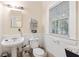 Cozy bathroom featuring a pedestal sink, a toilet, a window, and wainscoting at 348 7Th Ne St, Atlanta, GA 30308