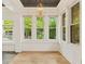 Light-filled sunroom with hardwood floors, a modern light fixture, and views of the lush outdoors at 28 Peachtree Hills Ne Ave, Atlanta, GA 30305