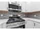 Modern kitchen featuring stainless steel appliances, a gas range, and stylish backsplash with white cabinets at 1272 Sherwood Dr, Norcross, GA 30093