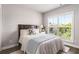 Bright bedroom featuring a bed with a floral pillow, a bedside table, and a large window with views of the trees outside at 4358 Parkside Pl, Atlanta, GA 30342