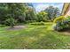 Scenic backyard with a wooden shed, flowering plants, and expansive green lawn at 2628 Tanglewood Rd, Decatur, GA 30033