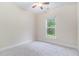 A basic bedroom with gray carpet and a double hung window overlooking green space at 129 Academy Ln, Canton, GA 30114