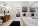 Bright bathroom featuring a soaking tub, neutral tile, and modern fixtures at 6403 Queens Court Trce, Mableton, GA 30126