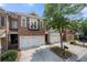 Townhouse exterior featuring brick facade, white garage doors, and a well-maintained front yard at 6403 Queens Court Trce, Mableton, GA 30126