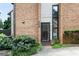 Inviting brick facade with modern black door, enhanced by lush greenery and an elongated window on the side at 3268 Clairmont North Ne Rd, Brookhaven, GA 30329