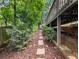 Stone path leads through the backyard with lush trees and access under the deck at 350 Fountain Oaks Ln, Atlanta, GA 30342